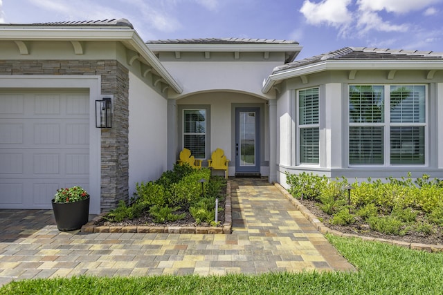 10339 SW Tetian Dr, Port Saint Lucie, FL 34987 - view of exterior entry with stone siding, stucco siding, an attached garage, and a tile roof