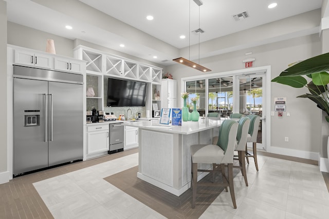 10339 SW Tetian Dr, Port Saint Lucie, FL 34987 - kitchen featuring built in fridge, a center island, backsplash, light countertops, and white cabinets