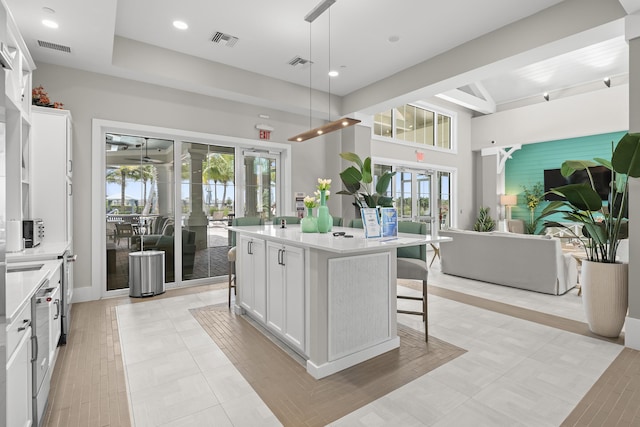 10339 SW Tetian Dr, Port Saint Lucie, FL 34987 - kitchen with open floor plan, a breakfast bar, white cabinets, a kitchen island, and light countertops
