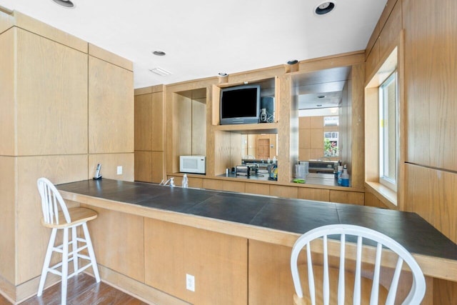 1825 Palm Cove Blvd Unit 7-307, Delray Beach, FL 33445 - kitchen with white microwave, wood finished floors, tile countertops, a breakfast bar, and light brown cabinets