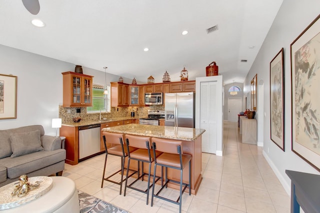 5630 Eagle Trace Ct, Lake Worth, FL 33463 - kitchen with stainless steel appliances, a sink, open floor plan, brown cabinetry, and backsplash