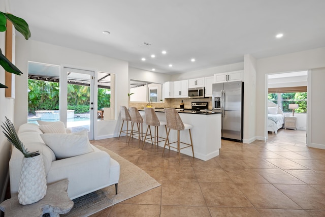 330 SE 7th Ave, Delray Beach, FL 33483 - kitchen featuring appliances with stainless steel finishes, backsplash, open floor plan, white cabinets, and a peninsula