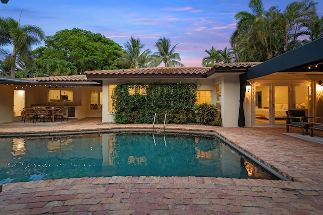 330 SE 7th Ave, Delray Beach, FL 33483 - pool at dusk featuring a patio area, french doors, and an outdoor pool