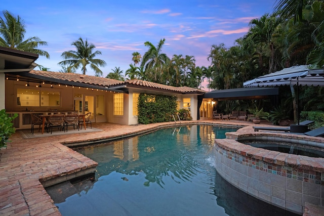 330 SE 7th Ave, Delray Beach, FL 33483 - pool at dusk featuring a patio area, outdoor dining area, and a pool with connected hot tub