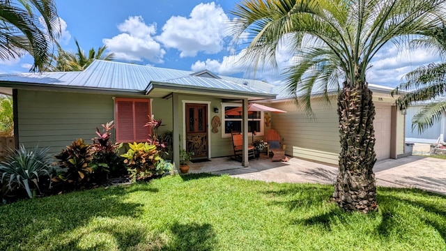 3725 SE Middle St, Stuart, FL 34997 - view of front of property featuring concrete driveway, a front lawn, an attached garage, and metal roof