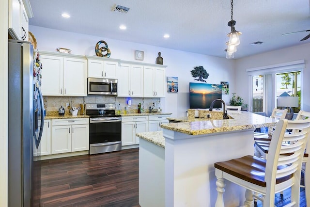 5333 SE Celestial Cir, Stuart, FL 34997 - kitchen featuring appliances with stainless steel finishes, dark wood-type flooring, decorative backsplash, white cabinetry, and a breakfast bar