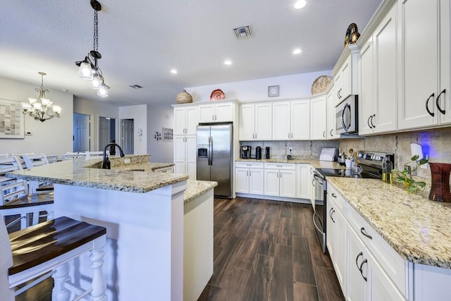 5333 SE Celestial Cir, Stuart, FL 34997 - kitchen with appliances with stainless steel finishes, recessed lighting, dark wood-style flooring, white cabinets, and a spacious island