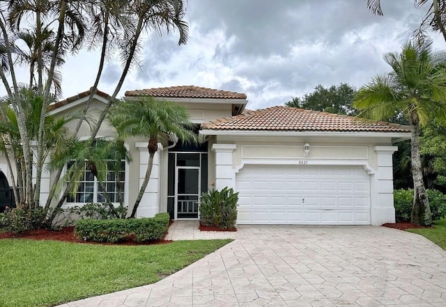8825 Gibson Cay, West Palm Beach, FL 33411 - mediterranean / spanish-style home featuring an attached garage, driveway, a tiled roof, stucco siding, and a front yard