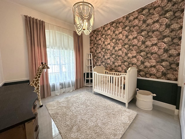 8825 Gibson Cay, West Palm Beach, FL 33411 - unfurnished bedroom featuring a chandelier, wallpapered walls, a wainscoted wall, a nursery area, and baseboards