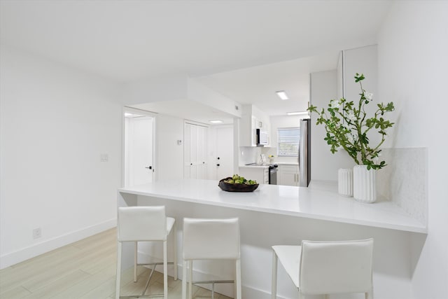 700 NE Harbour Ter Unit 3320, Boca Raton, FL 33431 - kitchen featuring electric stove, a peninsula, light countertops, a kitchen breakfast bar, and freestanding refrigerator