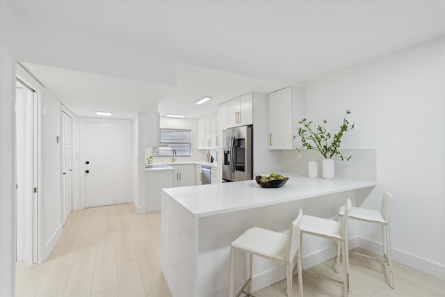 700 NE Harbour Ter Unit 3320, Boca Raton, FL 33431 - kitchen with stainless steel appliances, light countertops, a peninsula, a breakfast bar, and white cabinets