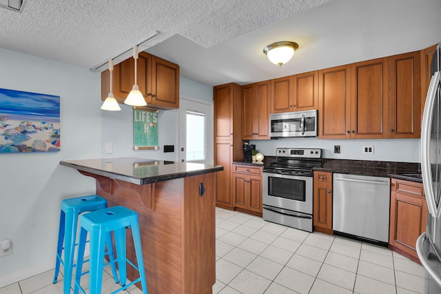 1 Harbourside Dr Unit 4506, Delray Beach, FL 33483 - kitchen featuring stainless steel appliances, brown cabinets, a breakfast bar, a textured ceiling, and light tile patterned flooring