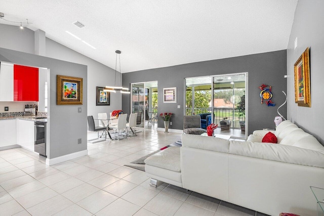 7685 Springwater Pl Unit 201, Boynton Beach, FL 33437 - living room featuring vaulted ceiling, a textured ceiling, light tile patterned floors, and baseboards