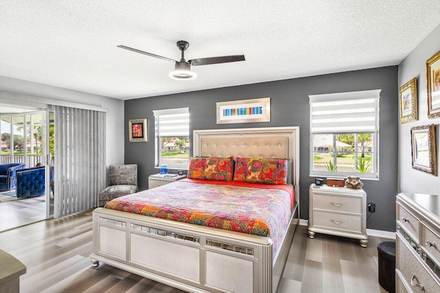 7685 Springwater Pl Unit 201, Boynton Beach, FL 33437 - bedroom featuring access to outside, multiple windows, dark wood-style floors, a textured ceiling, and a ceiling fan