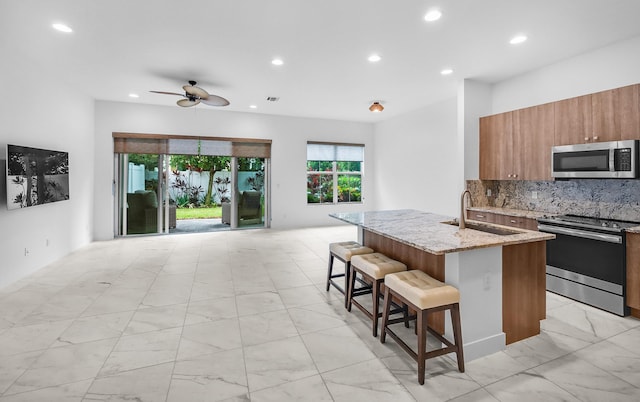 4829 Pointe Midtown Rd Unit 4829, Palm Beach Gardens, FL 33418 - kitchen featuring stainless steel appliances, a sink, recessed lighting, brown cabinetry, and light stone counters