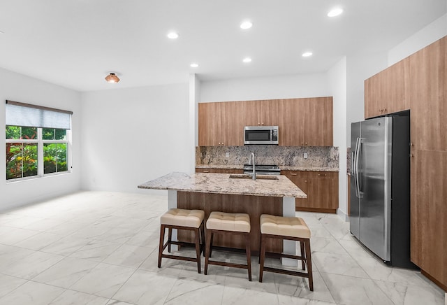 4829 Pointe Midtown Rd Unit 4829, Palm Beach Gardens, FL 33418 - kitchen featuring stainless steel appliances, a sink, a breakfast bar, brown cabinetry, and decorative backsplash