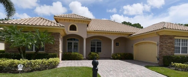 9320 Scarborough Ct, Port Saint Lucie, FL 34986 - view of front facade featuring a garage, decorative driveway, a tiled roof, stucco siding, and stone siding