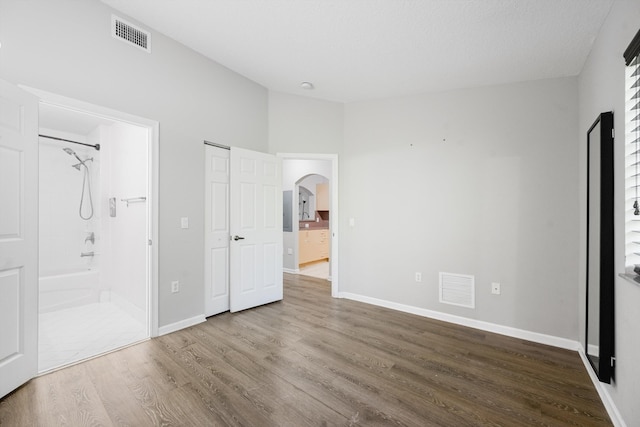 3710 N Jog Rd Unit 202, West Palm Beach, FL 33411 - unfurnished bedroom with wood finished floors, arched walkways, ensuite bathroom, and baseboards