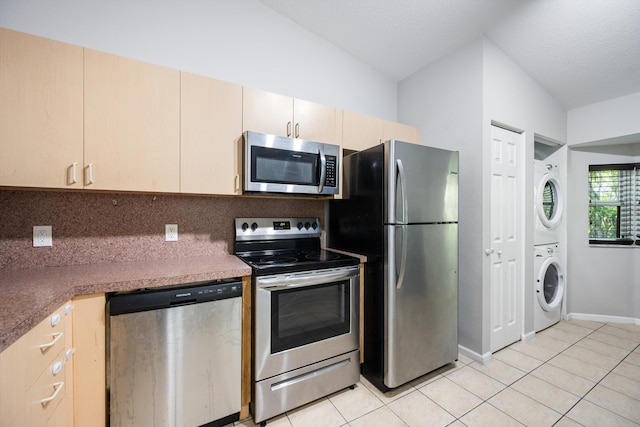 3710 N Jog Rd Unit 202, West Palm Beach, FL 33411 - kitchen with appliances with stainless steel finishes, stacked washer / dryer, light tile patterned floors, light brown cabinets, and vaulted ceiling