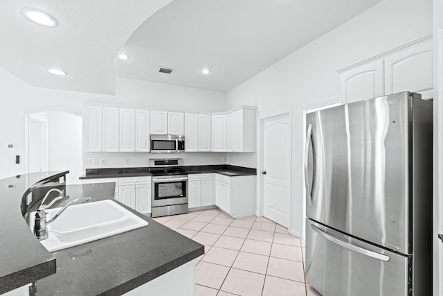 11356 Ira Ln, Lake Worth, FL 33449 - kitchen featuring stainless steel appliances, arched walkways, a sink, dark countertops, and light tile patterned floors