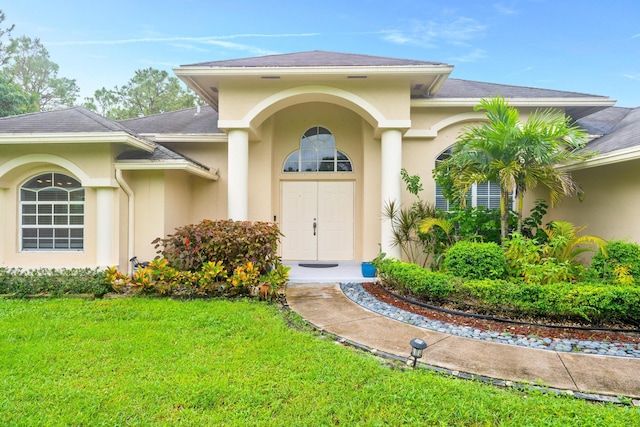 11356 Ira Ln, Lake Worth, FL 33449 - view of exterior entry with a yard, stucco siding, and a shingled roof