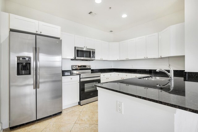 3960 N Flagler Dr Unit 305, West Palm Beach, FL 33407 - kitchen featuring stainless steel appliances, a peninsula, a sink, dark stone countertops, and recessed lighting
