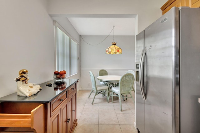 263 Preston Unit G, Boca Raton, FL 33434 - kitchen featuring stainless steel fridge with ice dispenser, dark countertops, light tile patterned floors, brown cabinetry, and hanging light fixtures