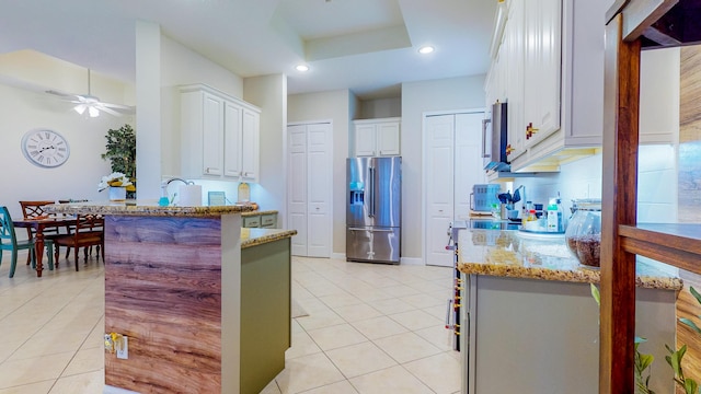 7144 Maidstone Dr, Port Saint Lucie, FL 34986 - kitchen with stainless steel refrigerator with ice dispenser, a peninsula, light tile patterned floors, light stone counters, and a ceiling fan
