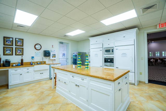 7144 Maidstone Dr, Port Saint Lucie, FL 34986 - kitchen featuring stainless steel appliances, white cabinets, a paneled ceiling, a warming drawer, and a sink