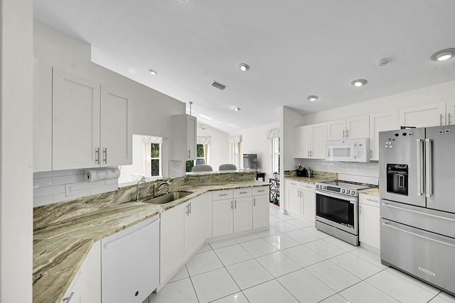 6078 Slice Ct, Boynton Beach, FL 33437 - kitchen with stainless steel appliances, tasteful backsplash, lofted ceiling, light stone countertops, and white cabinetry