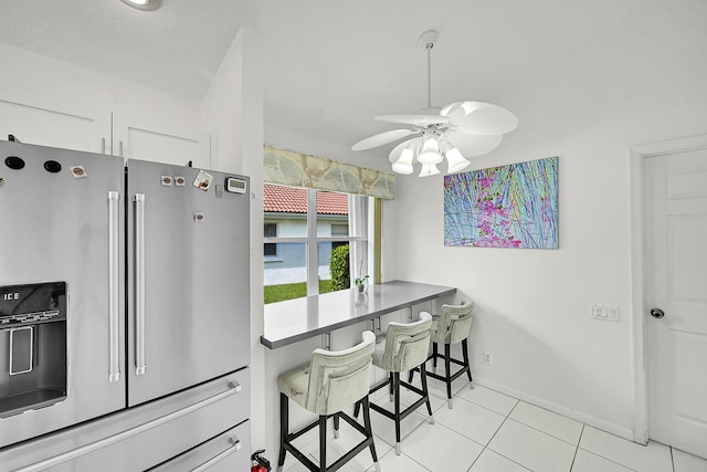 6078 Slice Ct, Boynton Beach, FL 33437 - kitchen with stainless steel refrigerator with ice dispenser, a ceiling fan, light tile patterned floors, a kitchen bar, and white cabinets