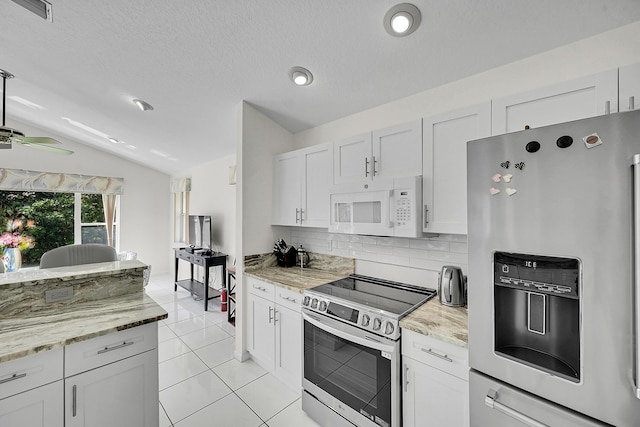 6078 Slice Ct, Boynton Beach, FL 33437 - kitchen with stainless steel appliances, vaulted ceiling, backsplash, light tile patterned floors, and white cabinetry