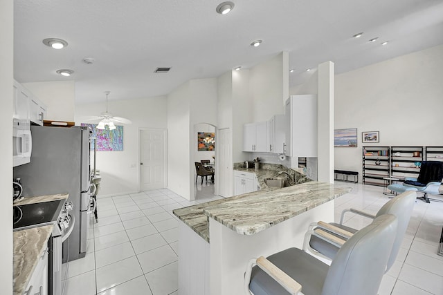6078 Slice Ct, Boynton Beach, FL 33437 - kitchen featuring stainless steel range with electric stovetop, ceiling fan, lofted ceiling, light tile patterned floors, and light stone counters