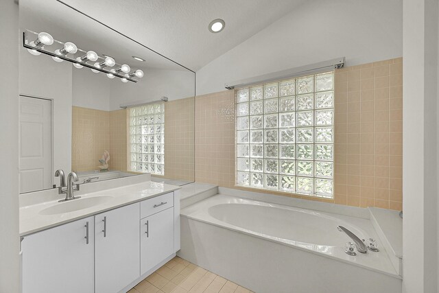 6078 Slice Ct, Boynton Beach, FL 33437 - full bath with lofted ceiling, a bath, vanity, tile patterned floors, and tile walls