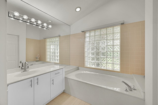 6078 Slice Ct, Boynton Beach, FL 33437 - bathroom featuring vaulted ceiling, a garden tub, vanity, tile patterned floors, and tile walls
