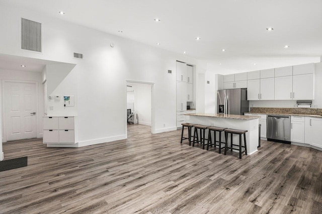 2802 Waters Edge Cir, Greenacres, FL 33413 - kitchen with stainless steel appliances, a kitchen island, wood finished floors, a towering ceiling, and a kitchen breakfast bar