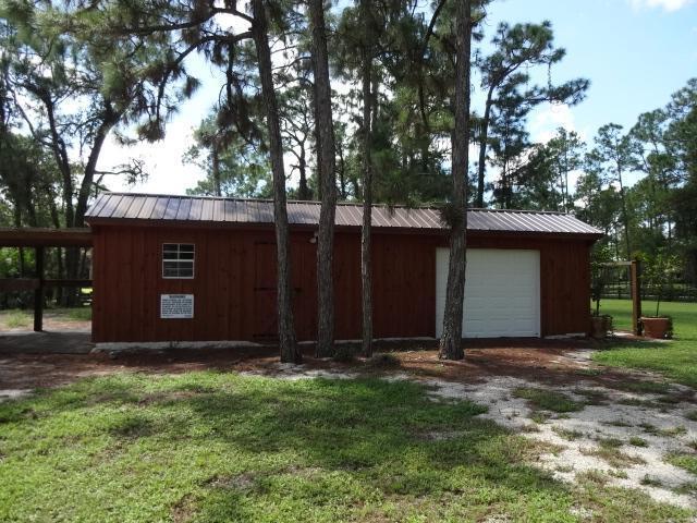 11357 Roselynn Way, Lake Worth, FL 33449 - view of side of property with an outbuilding, a yard, metal roof, driveway, and a detached garage