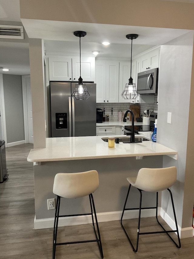 1530 SE Royal Green Cir Unit N103, Port Saint Lucie, FL 34952 - kitchen with stainless steel appliances, baseboards, white cabinets, and a peninsula