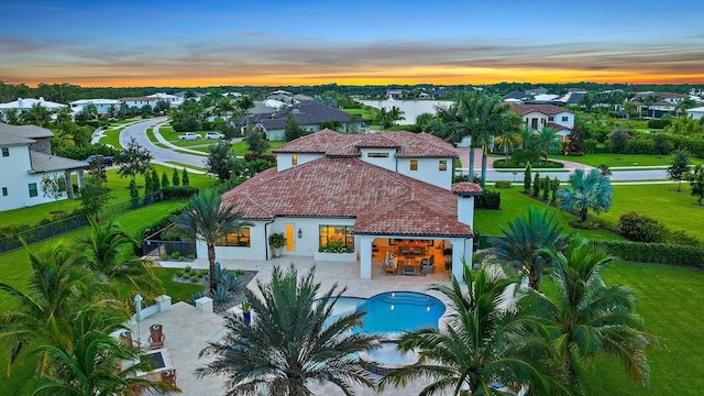 8164 SE Old Plantation Cir, Jupiter, FL 33458 - back of house at dusk with a tiled roof, stucco siding, an outdoor pool, a patio, and a residential view