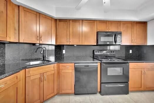 111 N N Pompano Beach Blvd Unit 411, Pompano Beach, FL 33062 - kitchen with black appliances, a sink, dark stone countertops, decorative backsplash, and light tile patterned floors