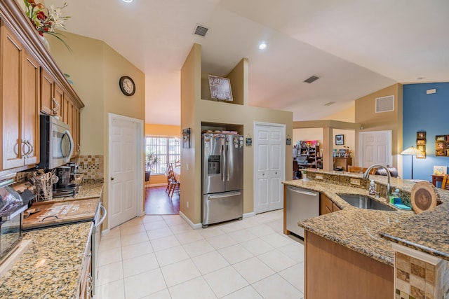3542 SW Rosardo St, Port Saint Lucie, FL 34953 - kitchen featuring stainless steel appliances, a sink, lofted ceiling, light tile patterned floors, and brown cabinetry