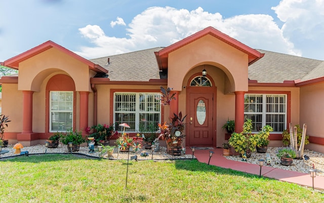 3542 SW Rosardo St, Port Saint Lucie, FL 34953 - view of exterior entry with roof with shingles, a lawn, and stucco siding