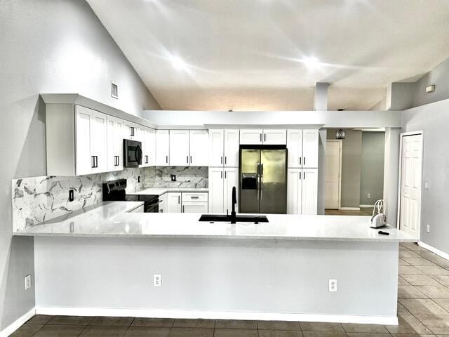 8065 99th Ct, Vero Beach, FL 32967 - kitchen with stainless steel fridge with ice dispenser, black microwave, range with electric stovetop, a peninsula, and tasteful backsplash