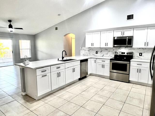 8065 99th Ct, Vero Beach, FL 32967 - kitchen with appliances with stainless steel finishes, arched walkways, a peninsula, backsplash, and light countertops