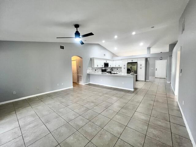 8065 99th Ct, Vero Beach, FL 32967 - unfurnished living room with lofted ceiling, ceiling fan, light tile patterned floors, arched walkways, and recessed lighting