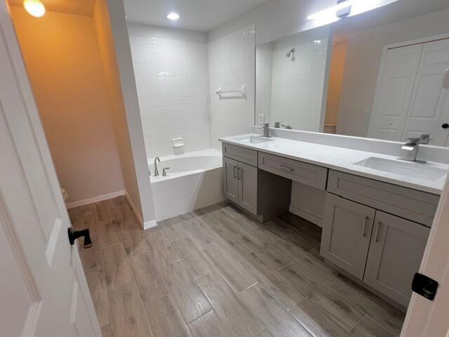 8065 99th Ct, Vero Beach, FL 32967 - full bathroom featuring double vanity, wood finished floors, tiled shower / bath, and recessed lighting