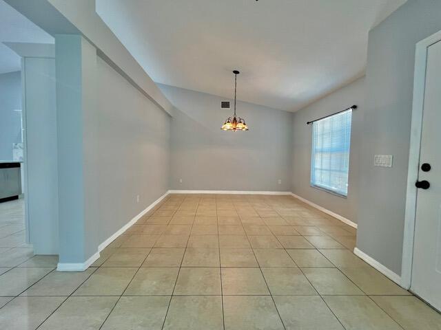8065 99th Ct, Vero Beach, FL 32967 - unfurnished dining area with lofted ceiling, light tile patterned flooring, and a chandelier