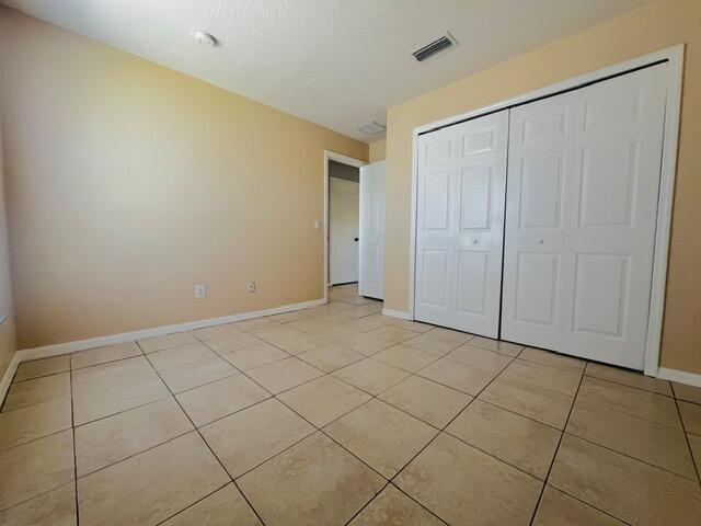 8065 99th Ct, Vero Beach, FL 32967 - unfurnished bedroom with light tile patterned floors and a closet