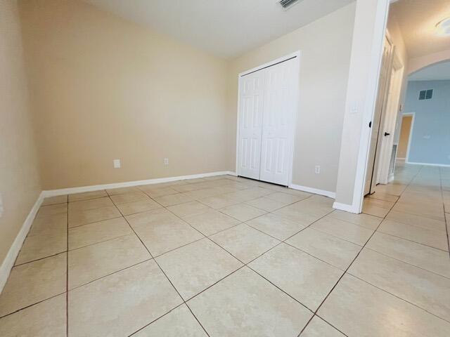 8065 99th Ct, Vero Beach, FL 32967 - unfurnished bedroom featuring light tile patterned floors, arched walkways, and a closet