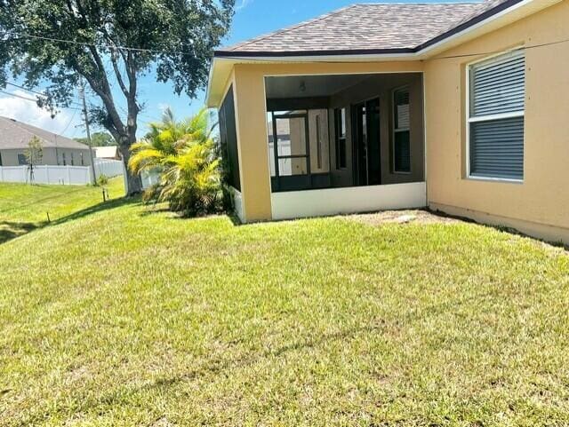 8065 99th Ct, Vero Beach, FL 32967 - back of house featuring a sunroom, a shingled roof, and stucco siding